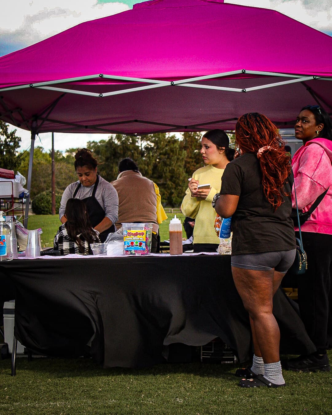 Families visiting a community health fair booth under a bright canopy