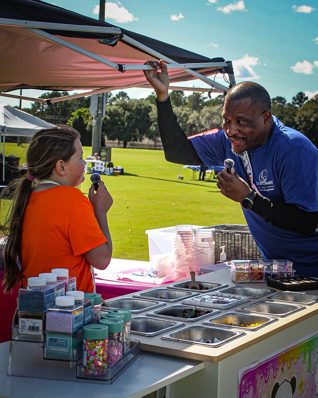 Greg Covert talking with a young entrepreneur at her colorful product booth